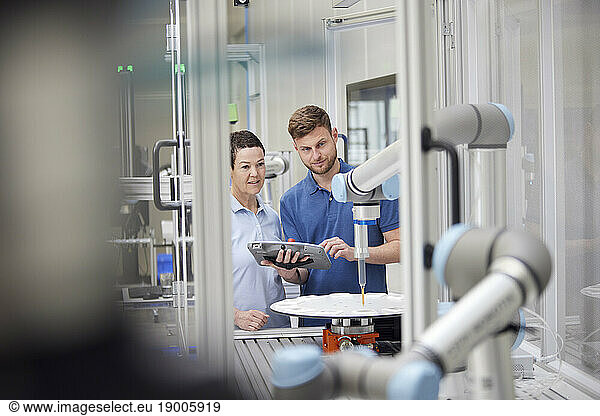 Technicians analyzing robotic machine in industry