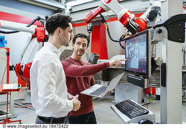 Technicians discussing together at robot factory
