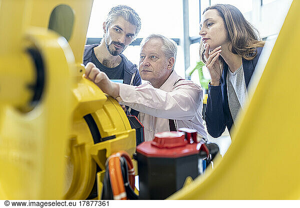 Technicians examining industrial robot in factory
