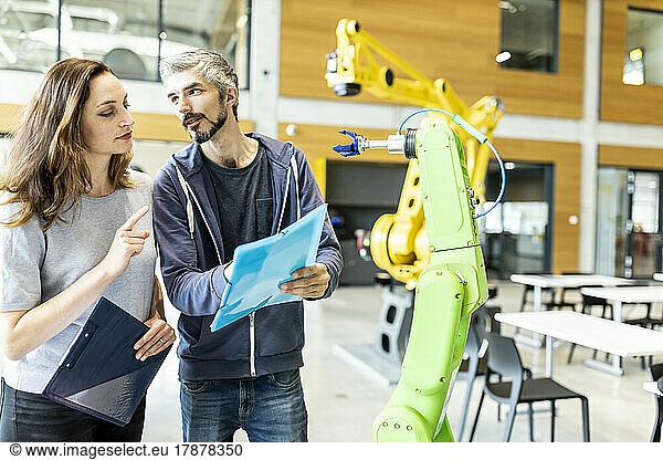 Technicians having meeting in front of industrial robot