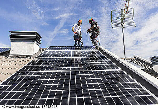 Technicians installing solar panel under sky on sunny day