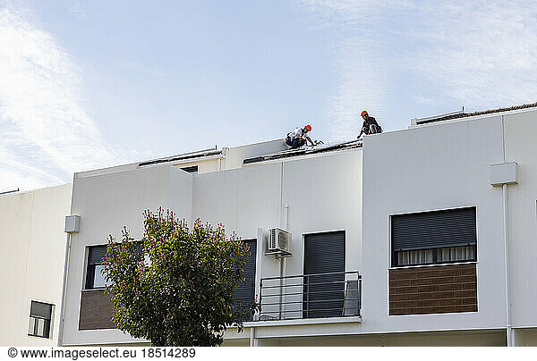 Technicians installing solar panels on roof