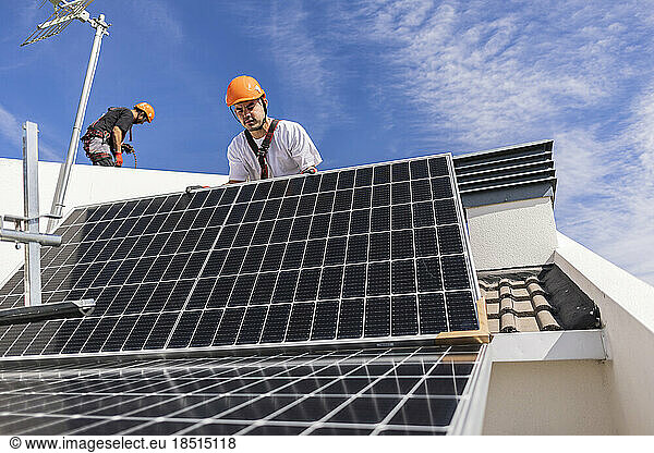 Technicians installing solar panels on rooftop