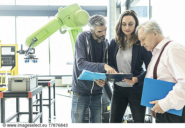 Technicians showing new industrial robot to senior colleague