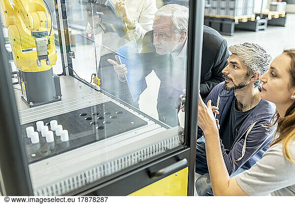 Technicians testing and observing new industrial robot