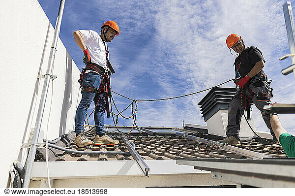 Technicians wearing safety harness standing on roof