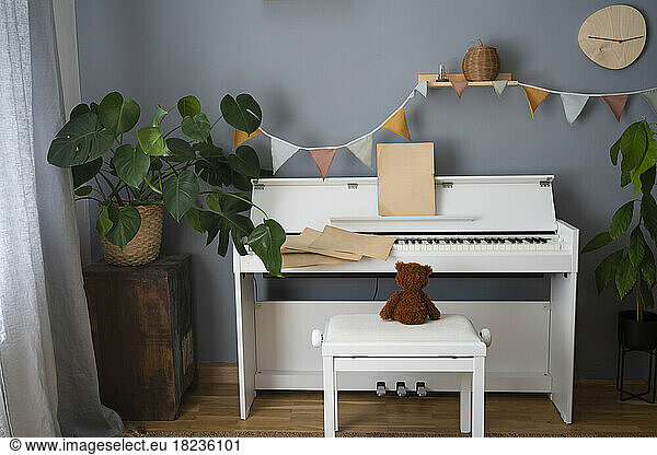 Teddy bear on seat by piano at home