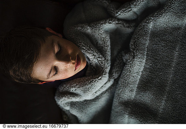 Teen boy cozy and covered in blanket