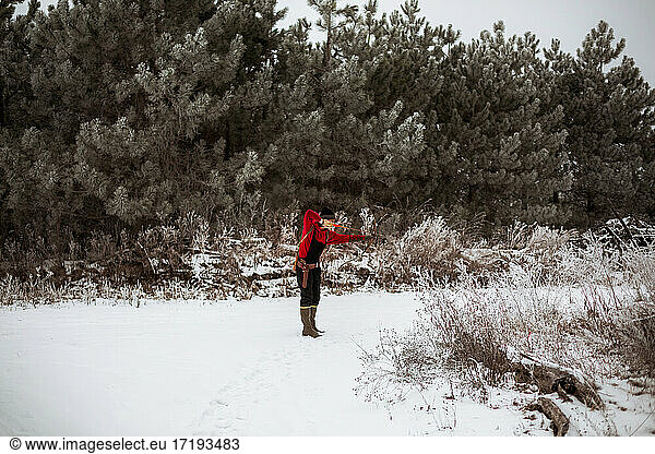 Teen boy shooting bow and arrow in wintery Wisconsin field