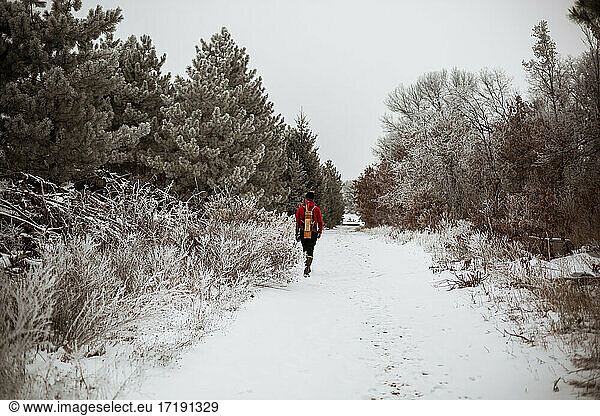 Teen boy walking away on a snowy winter Wisconsin road