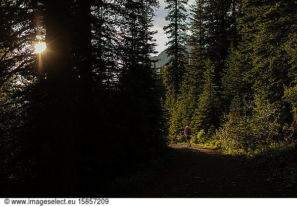 Teen boy walking on path in Canadian Rockies while sun sets