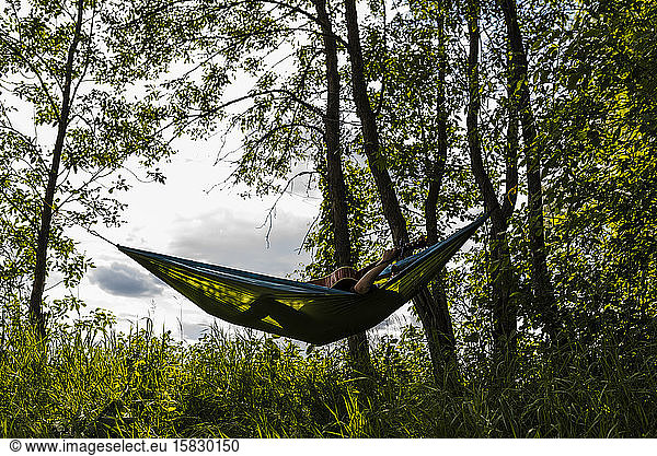 Teen Boys Plays Guitar While Relaxing in Hammock Outdoors