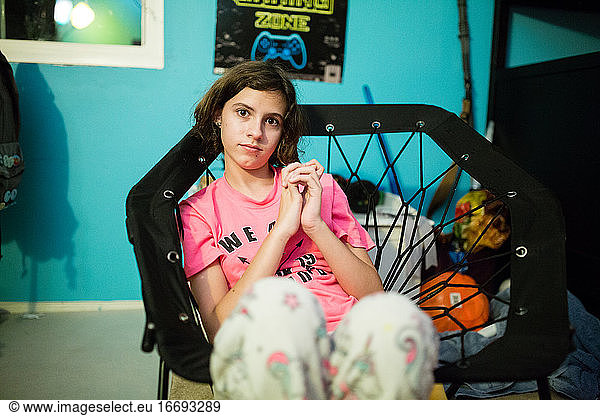 Teen girl clasps hands together while sitting in a bungee chair