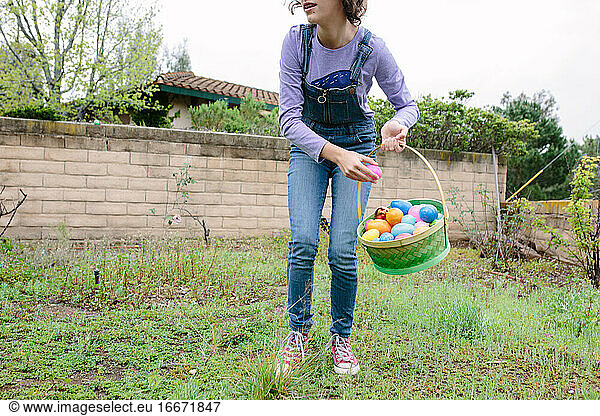 Teen girl collects plastic eggs on Easter to put in her basket