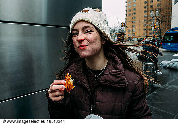 Teen girl eating bread on street corner