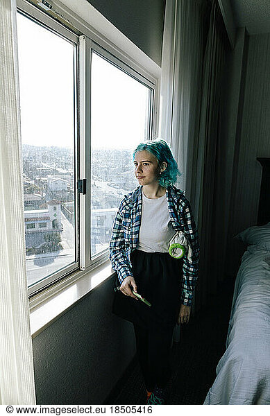 Teen Girl Holding Cellphone Looking Out Hotel Window