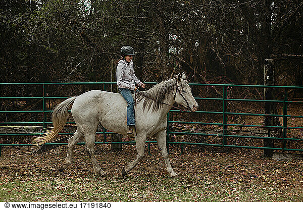 Teen girl in helmet riding horse bareback in round pen