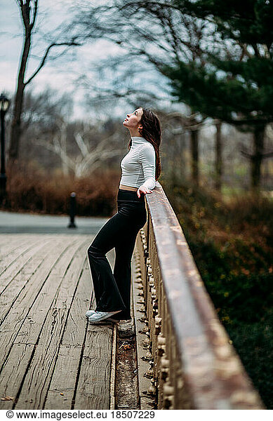 Teen girl looking up at sky on bridge