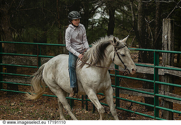 Teen girl loping grey mare bareback in round pen