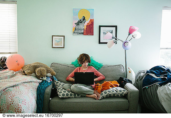 Teen girl on her laptop in her messy bedroom