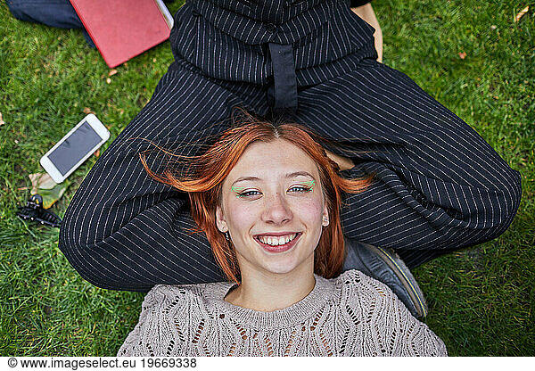 Teen girl resting on her girlfriend's lap in the meadow