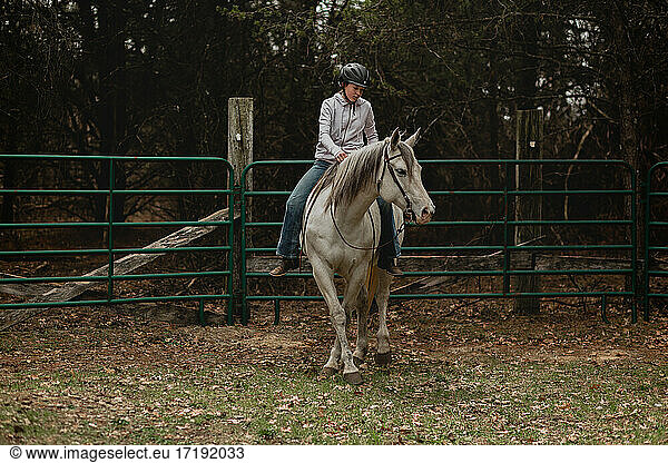 Teen girl riding grey mare bareback in round pen