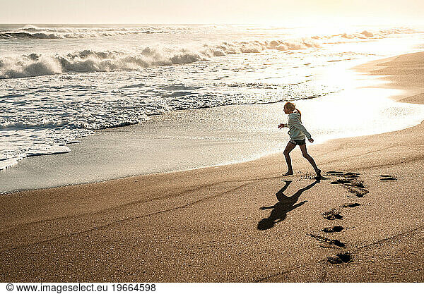 Teen girl running on beach at sunset