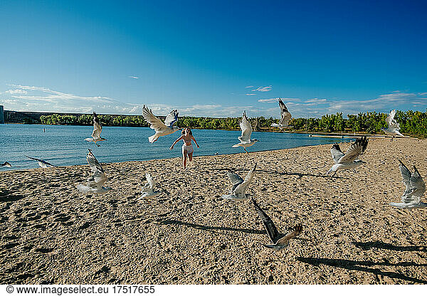 Teen girl running on beach chasing seagulls