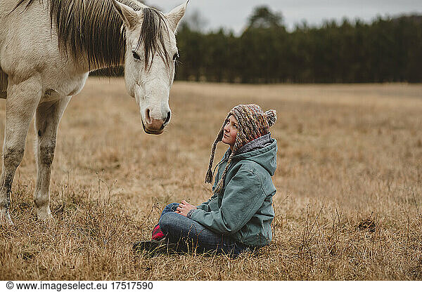 Teen girl sitting in front of horse