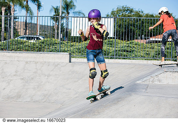 Teen girl skateboards at a skatepark while scratching her face