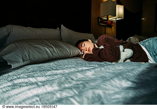 Teen girl sleeping on hotel bed in sunshine