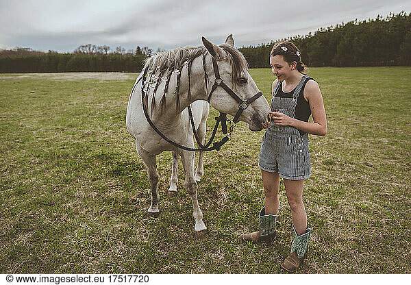 teen girl standing next to grey mare quarter horse with braids