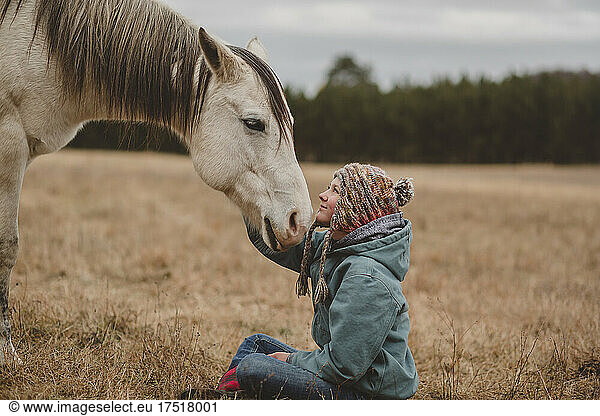 Teen girl touching horse head tenderly