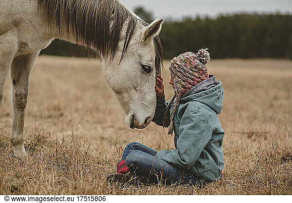 Teen girl touching horse on forehead in winter