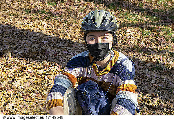 Teen Girl wearing Bicycle Helmet and Protective Mask  half-length seated Portrait