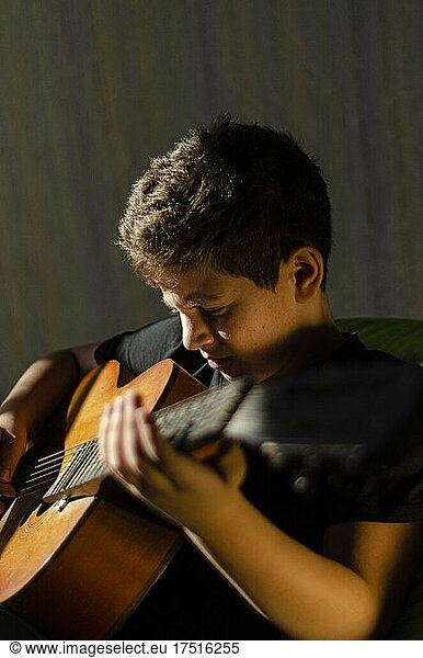teen in black t-shirt plays guitar