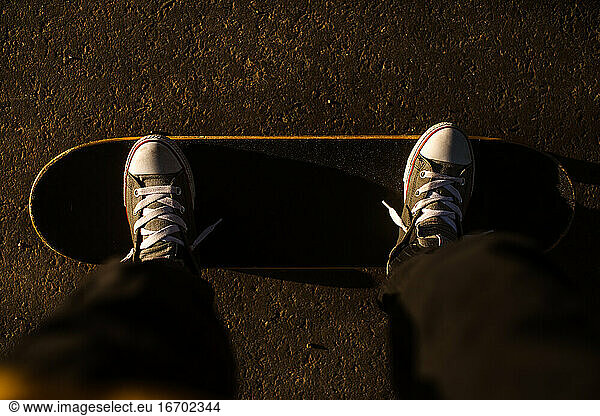 Teen looking down at feet on skateboard