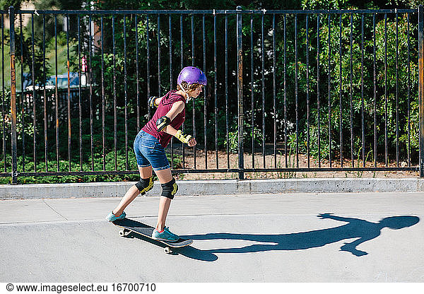 Teen skater girl skates at a skate park while wearing protective gear