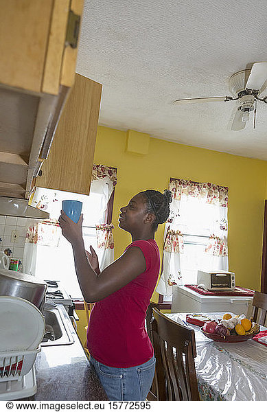 Teen suffering from Bipolar Disorder putting dishes away