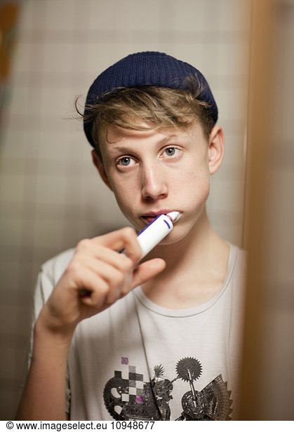 Teenage boy brushing teeth with electric toothbrush