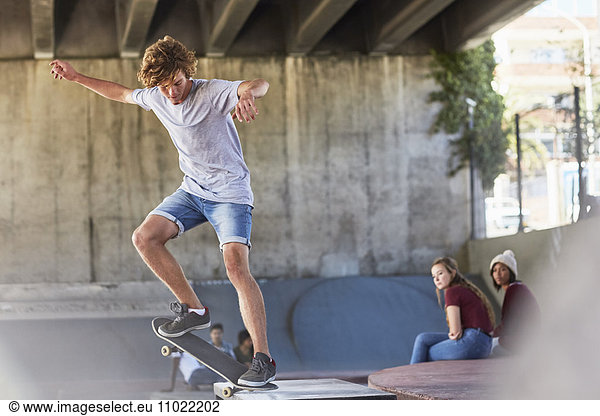 Teenage boy doing skateboard stunt at skate park