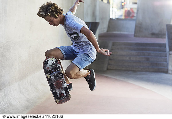 Teenage boy flipping skateboard at skate park