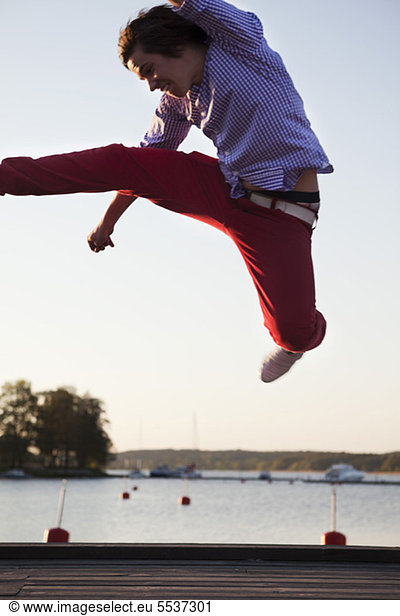Teenage boy jumping on jetty