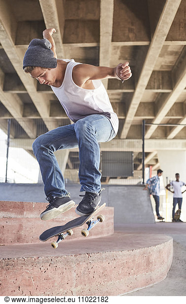 Teenage boy jumping skateboard at skate park