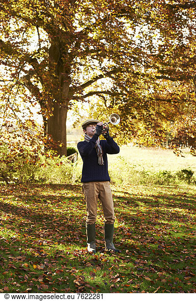 Teenage boy playing trumpet outdoors