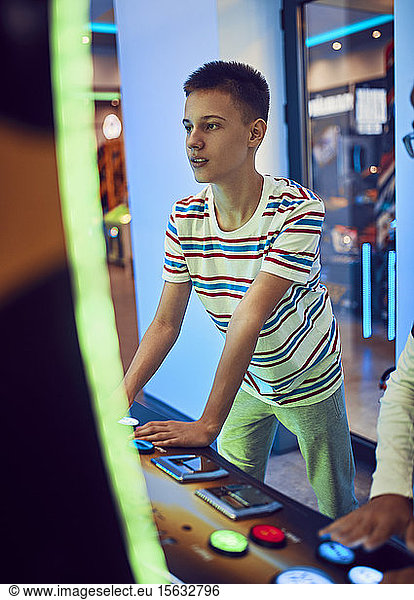Teenage boy playing with a gaming machine in an amusement arcade