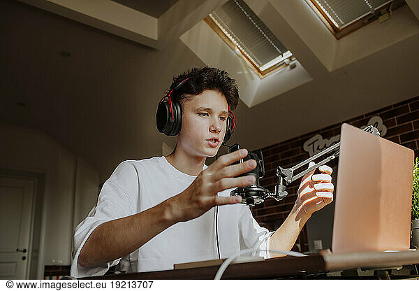 Teenage boy podcasting in front of laptop at home