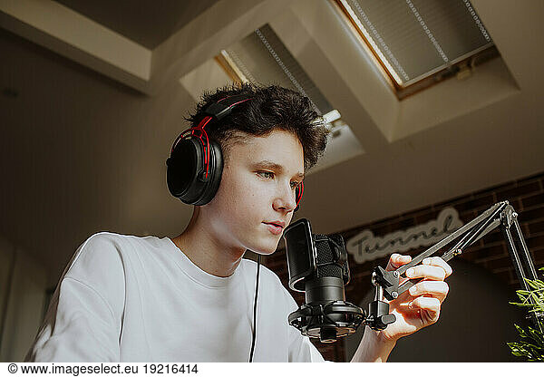Teenage boy podcasting though microphone at home