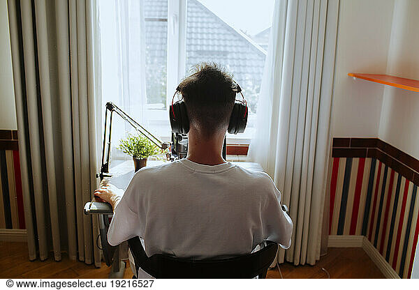 Teenage boy podcasting with microphone at home