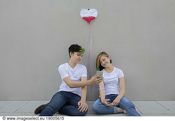Teenage boy showing mobile phone to girl connected with IV drip